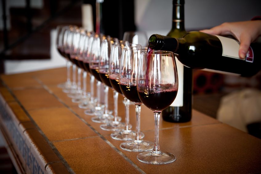 22119516 - woman hand with wine bottle pouring a row of glasses for tasting